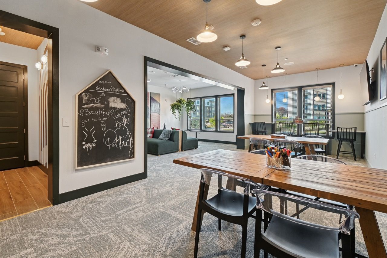Open communal lounge with a long wooden table, chairs, and a chalkboard wall.