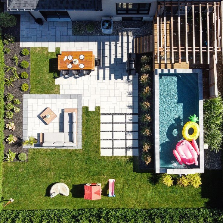 Vue aérienne d'un jardin comprenant un coin repas, un salon extérieur, une piscine rectangulaire et une pelouse.