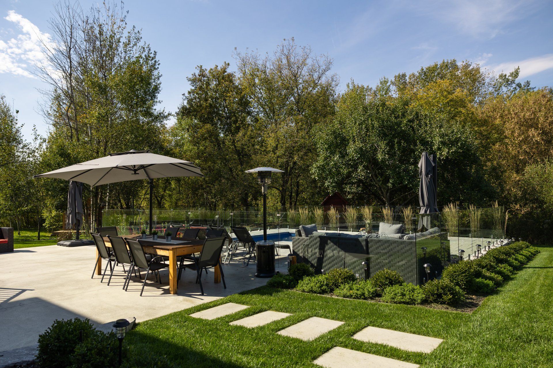 Une terrasse avec un foyer, des chaises Adirondack et un banc en pierre dans une cour arrière, agrémentée d'un mur de soutènement en pierre et de gazon.