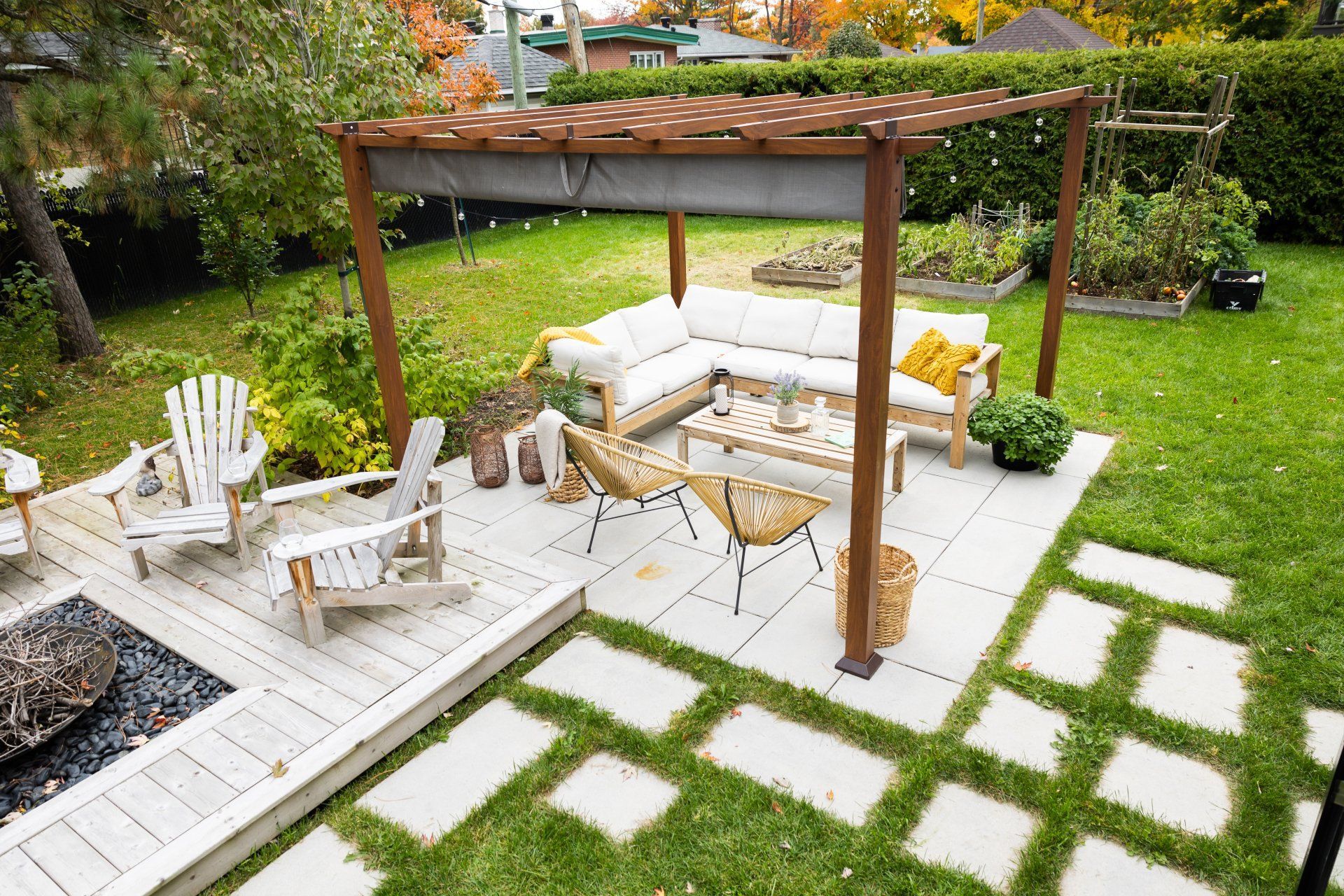 Un espace piscine dans le jardin comprenant une piscine bleu clair, un transat suspendu, des sièges en bois et une maison avec une terrasse.