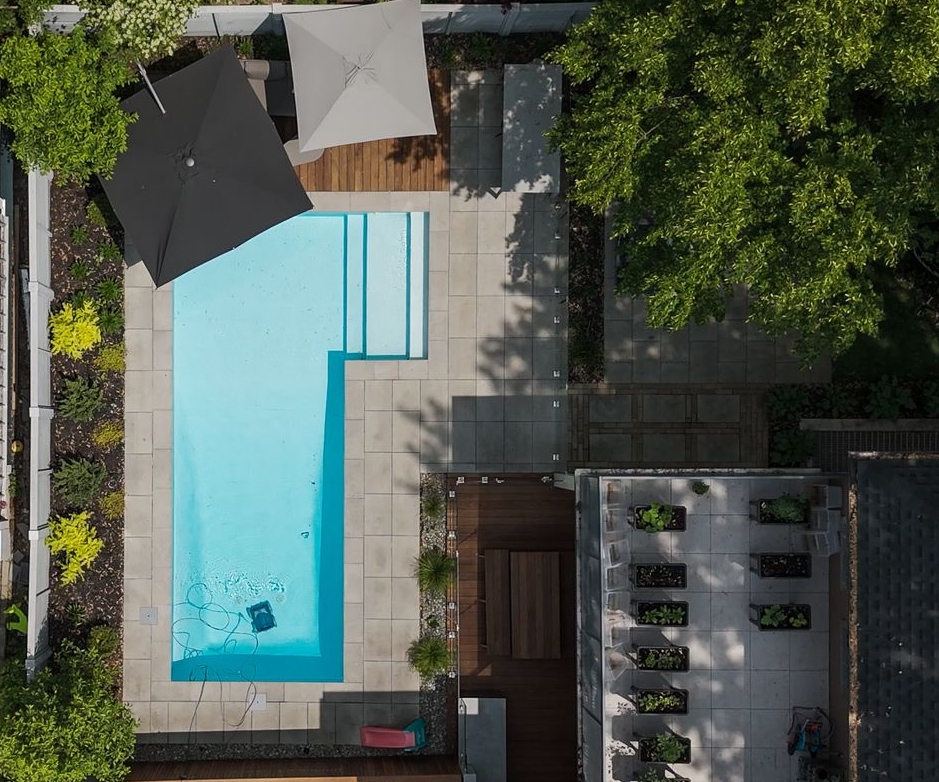 Canapé d'angle gris en forme de L avec table basse assortie sur une terrasse dans un jardin gazonné avec une cabane pour enfants.