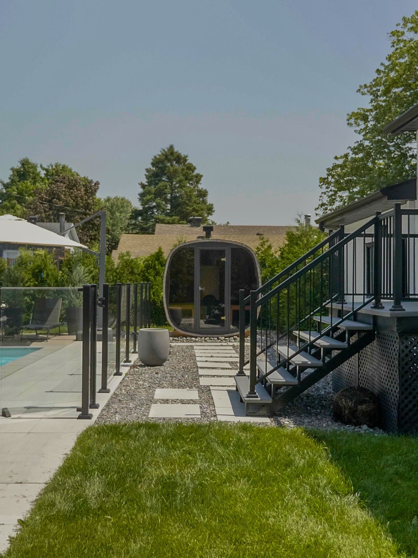 Une terrasse dans le jardin au coucher du soleil, avec un jacuzzi sous une pergola, un foyer et des sièges.