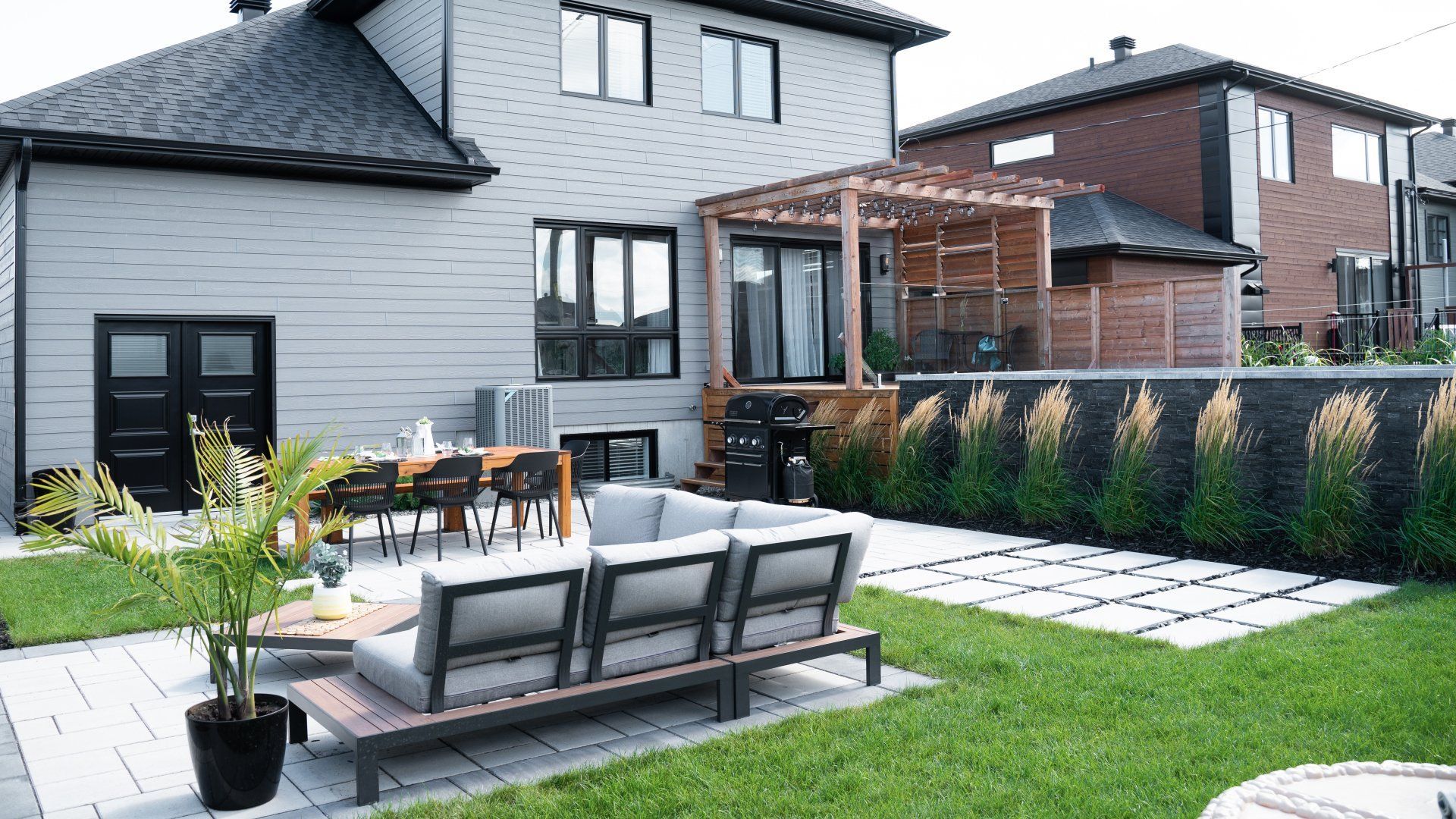 Vue aérienne d'une piscine rectangulaire dans un jardin avec un robot nettoyeur, une terrasse en pierre adjacente, une terrasse en bois et un espace jardin.