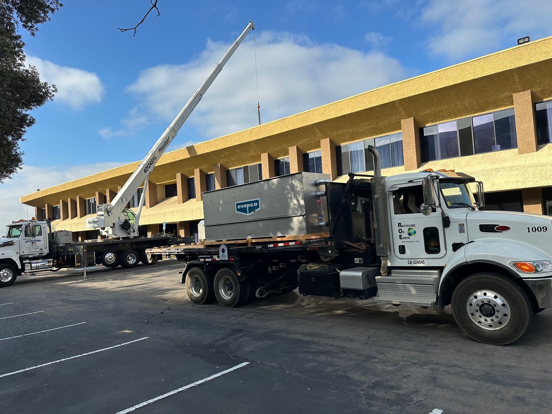 A truck with a crane on the back is parked in front of a building.