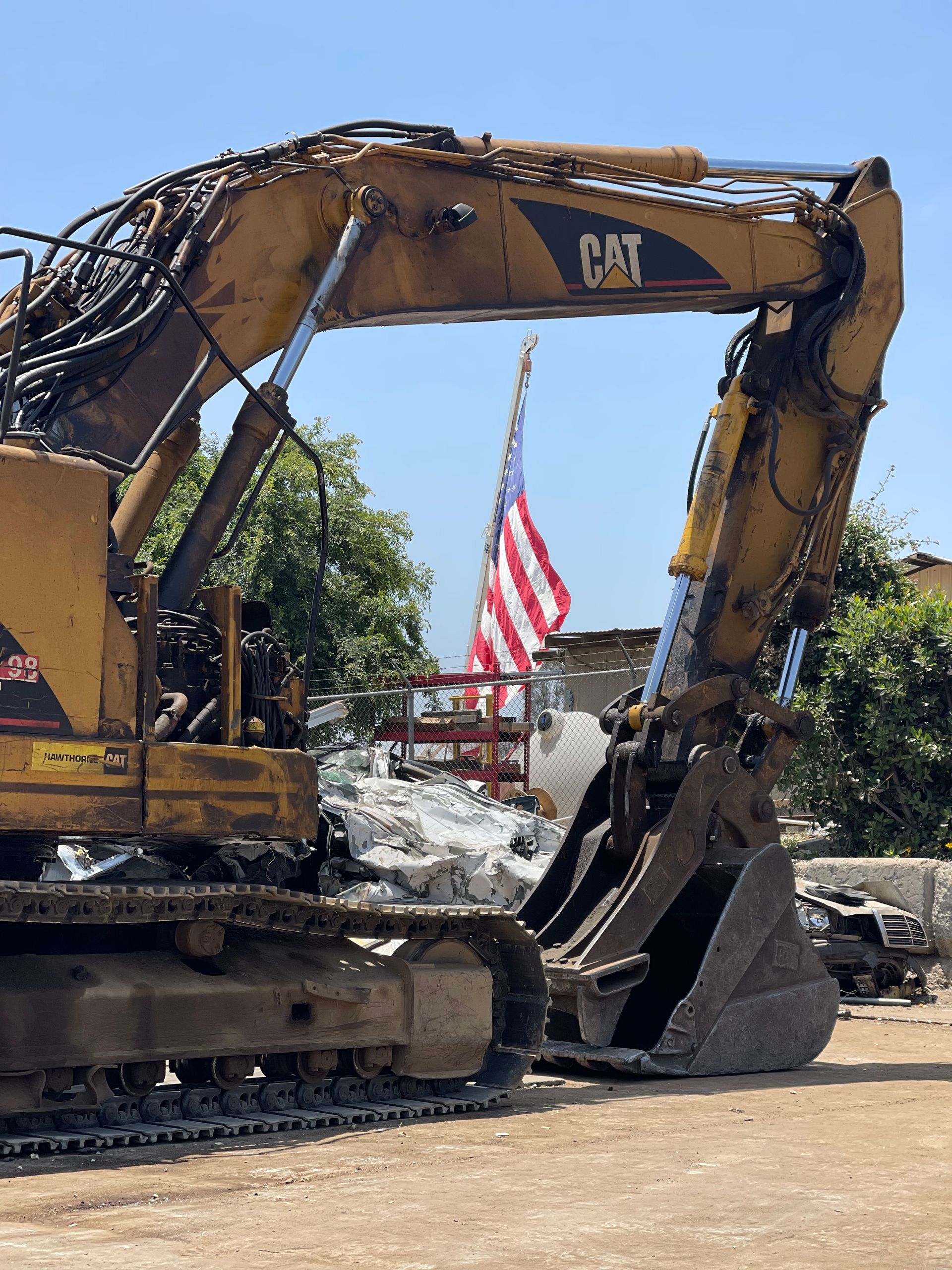 A cat excavator is parked in front of an american flag.