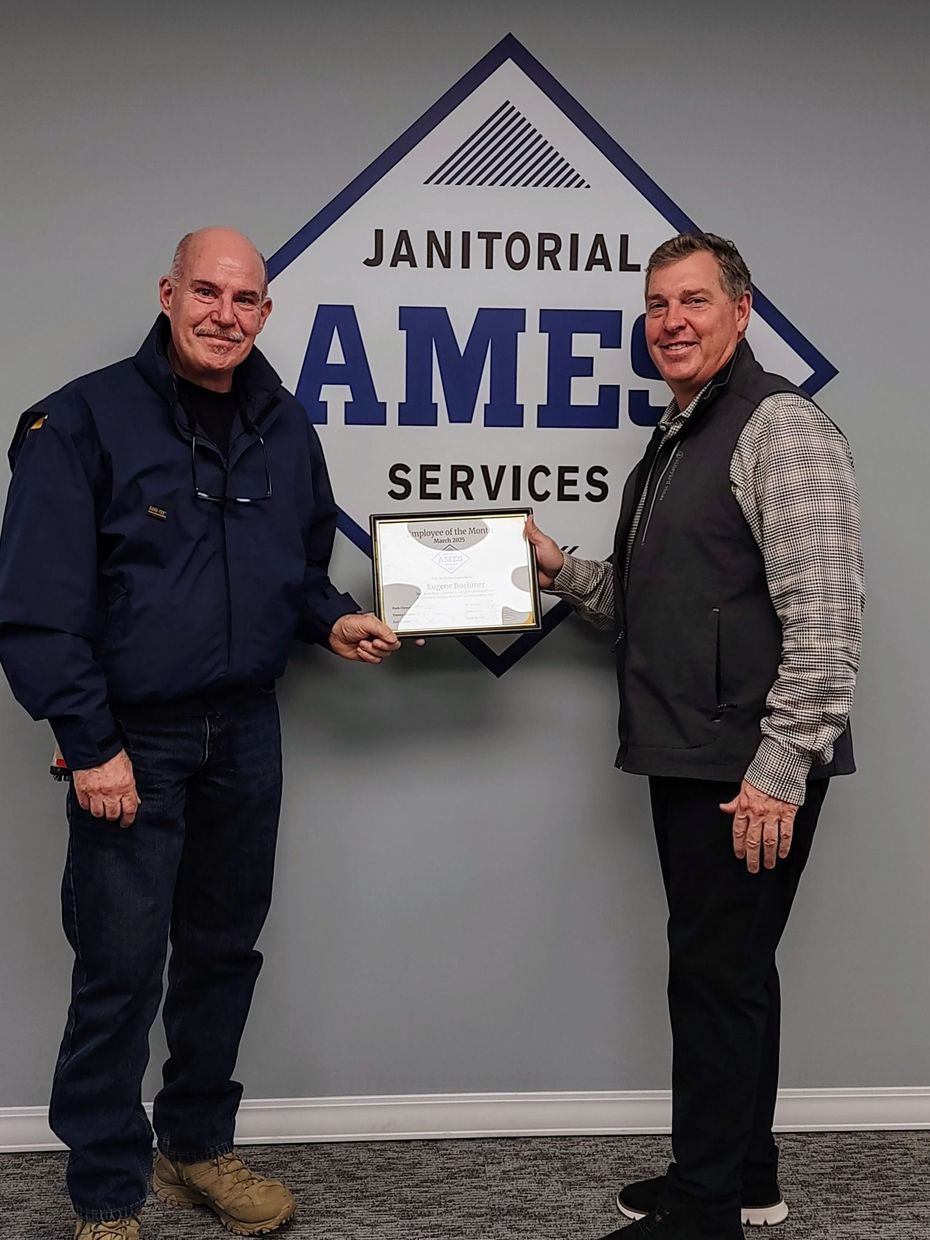 Two men holding a framed certificate in front of a 