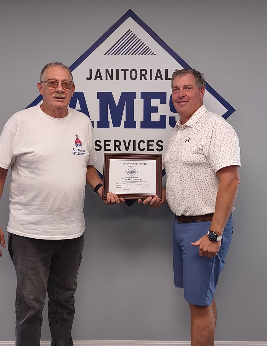 Two men holding a framed award in front of a Janitorial Services logo. 
