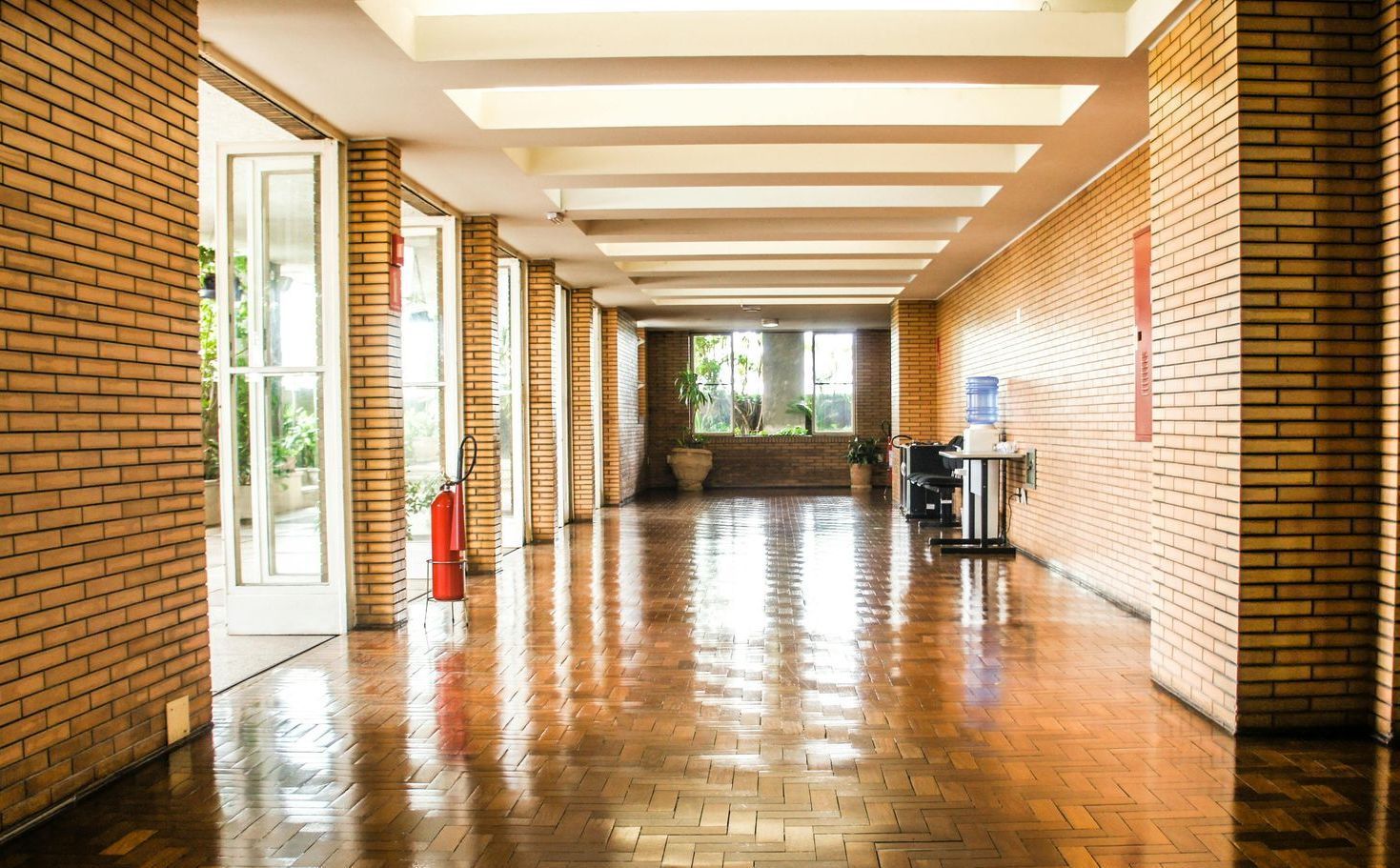 A long hallway with brick walls and a wooden floor of a middle school.