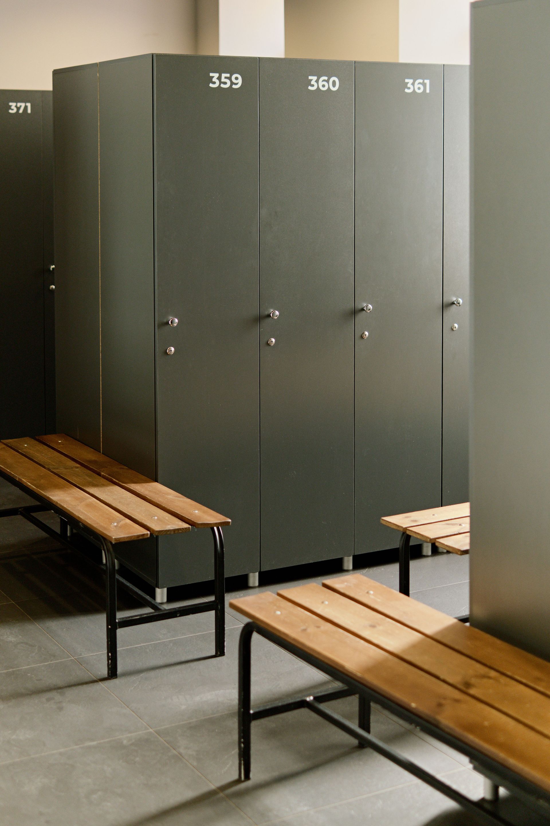 Locker room with gray lockers numbered 359–361 and wooden benches in the foreground