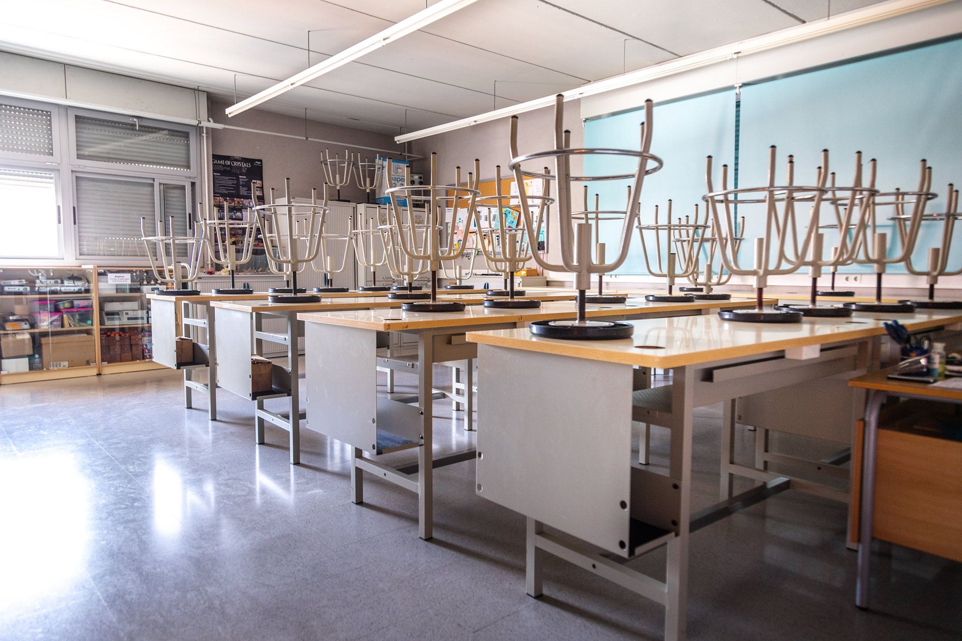Empty classroom with desks and chairs stacked on top. Windows and a whiteboard are visible.