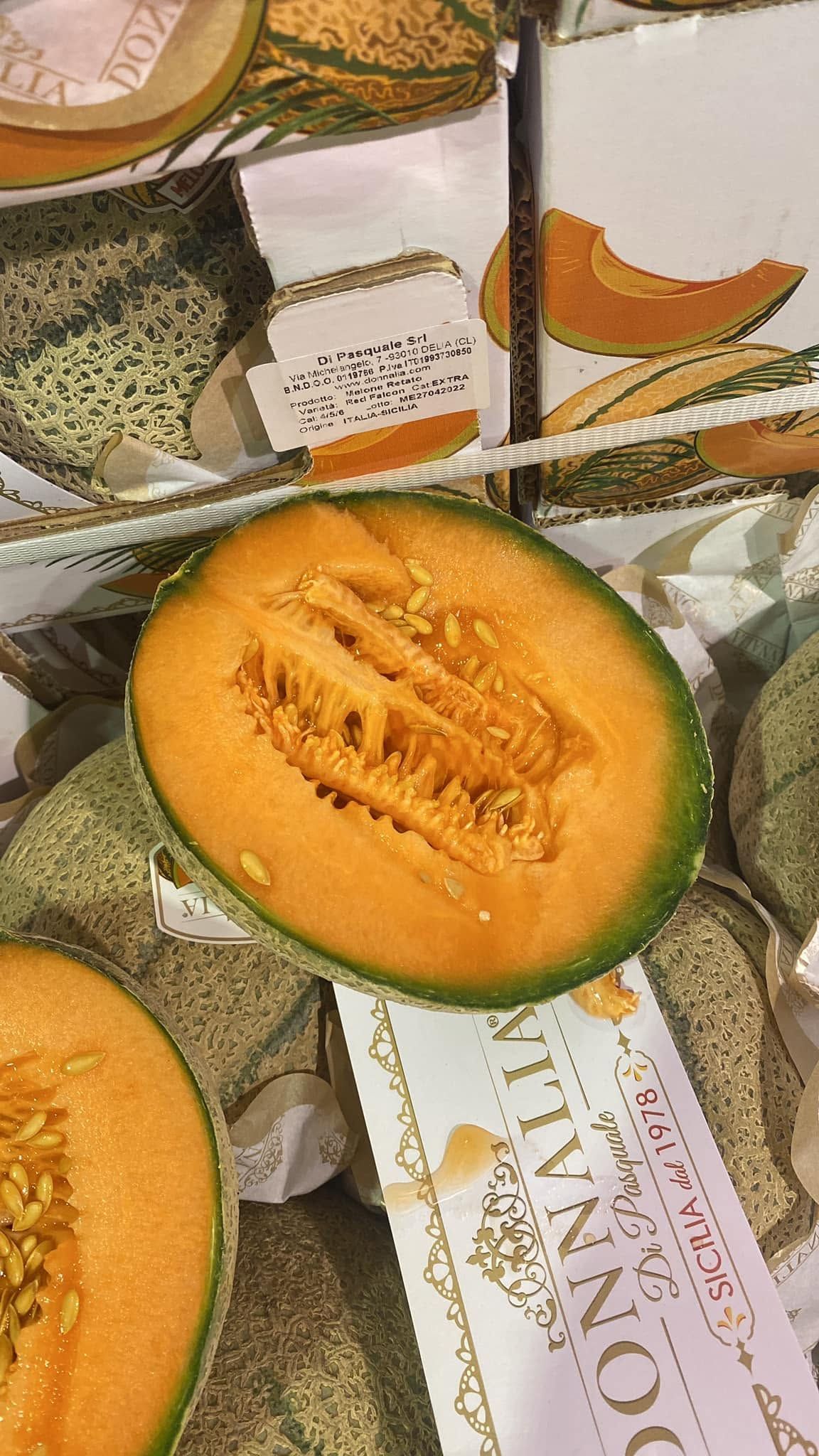 Melone cantalupo a fette con la buccia verde su carta da imballaggio decorata, con la polpa arancione e i semi in vista.