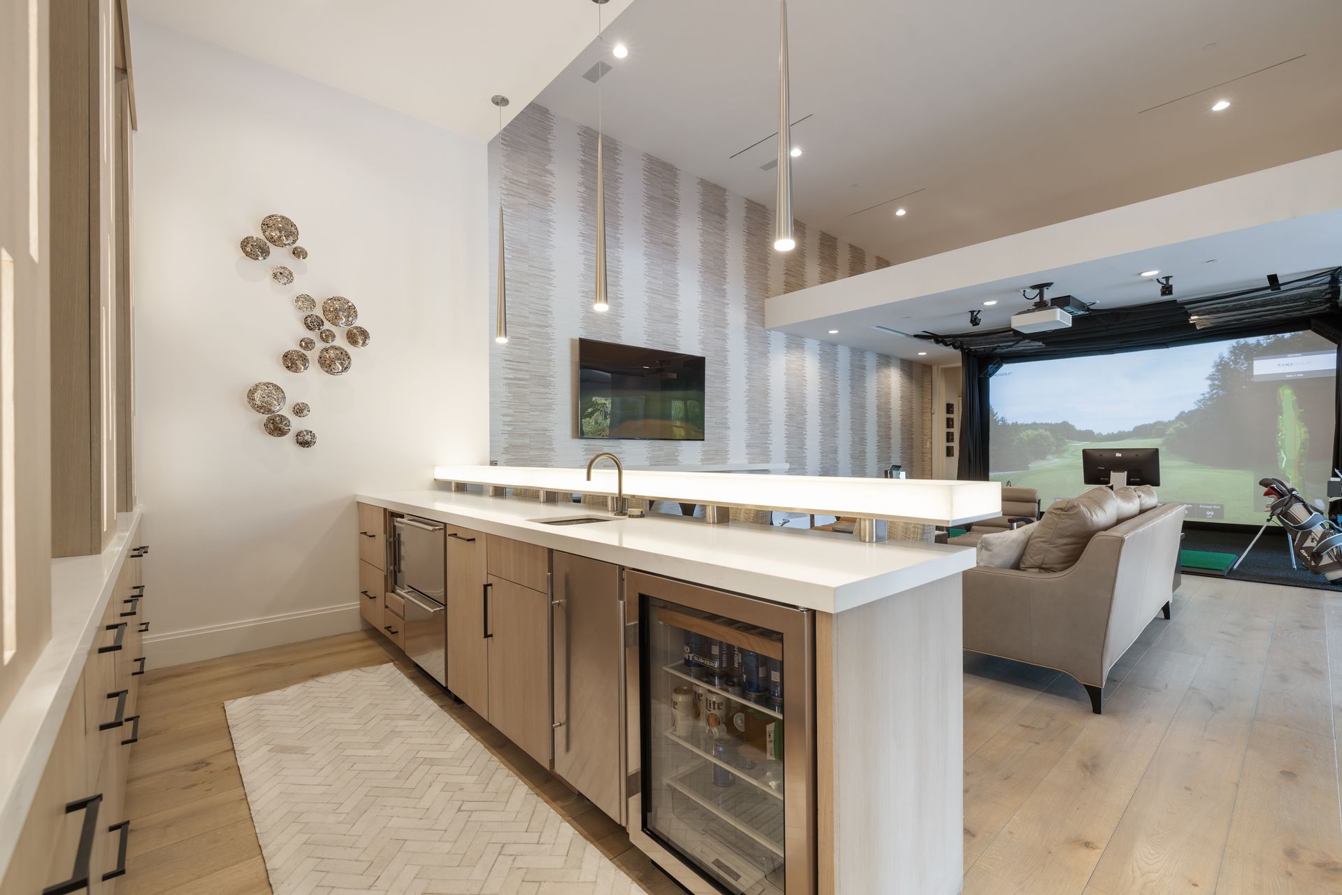 A kitchen with a bar and a golf simulator in the background.