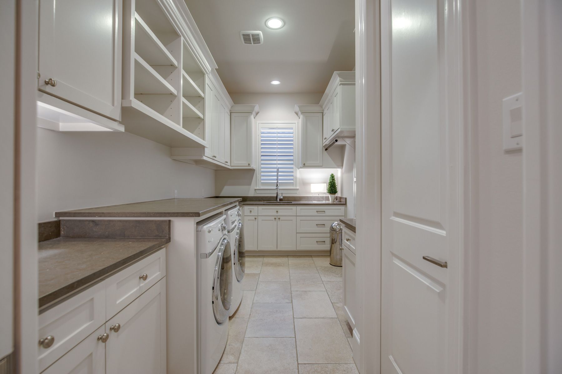 A laundry room with white cabinets , a washer and dryer , and a sink.