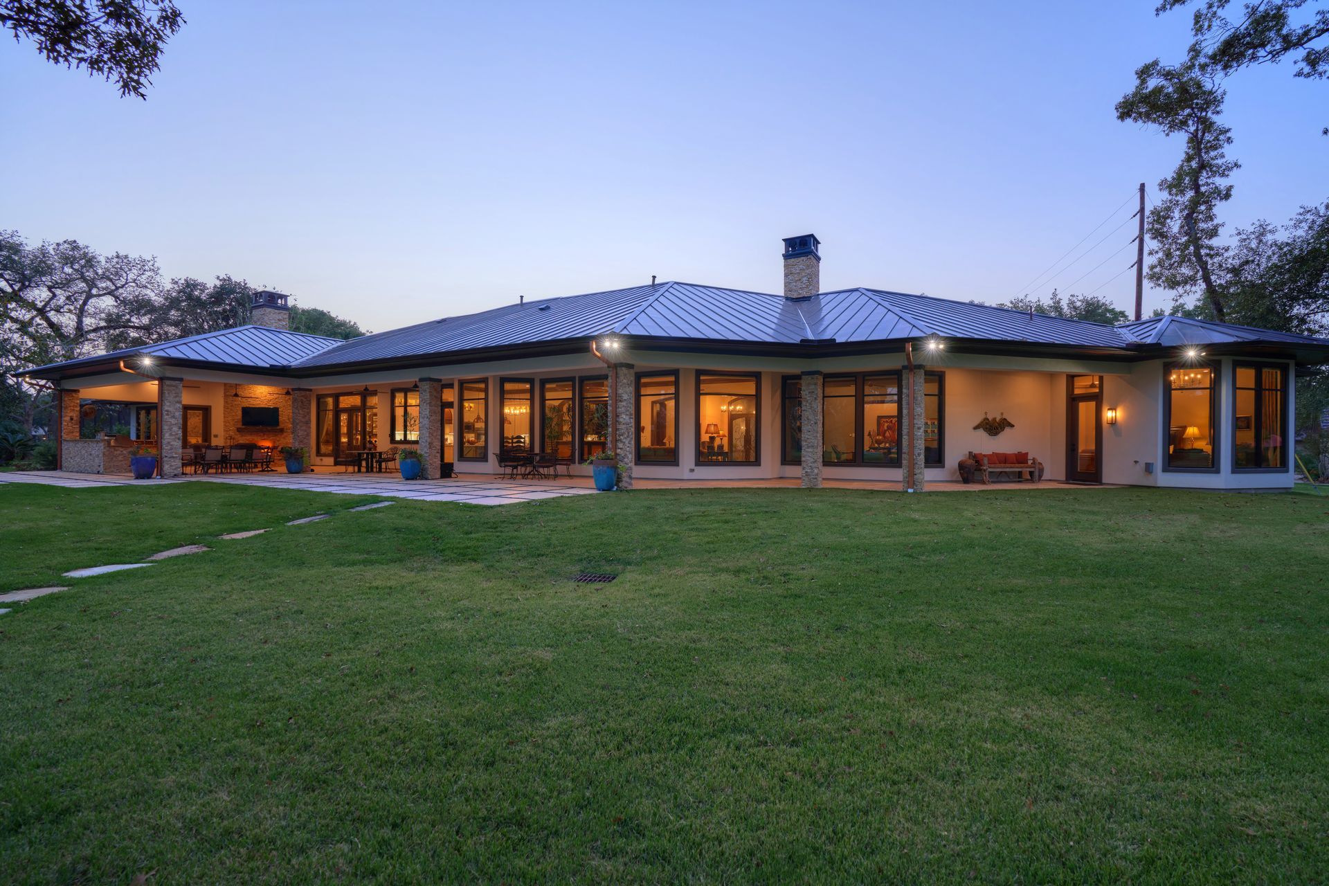 A large house with a lot of windows is sitting on top of a lush green field.