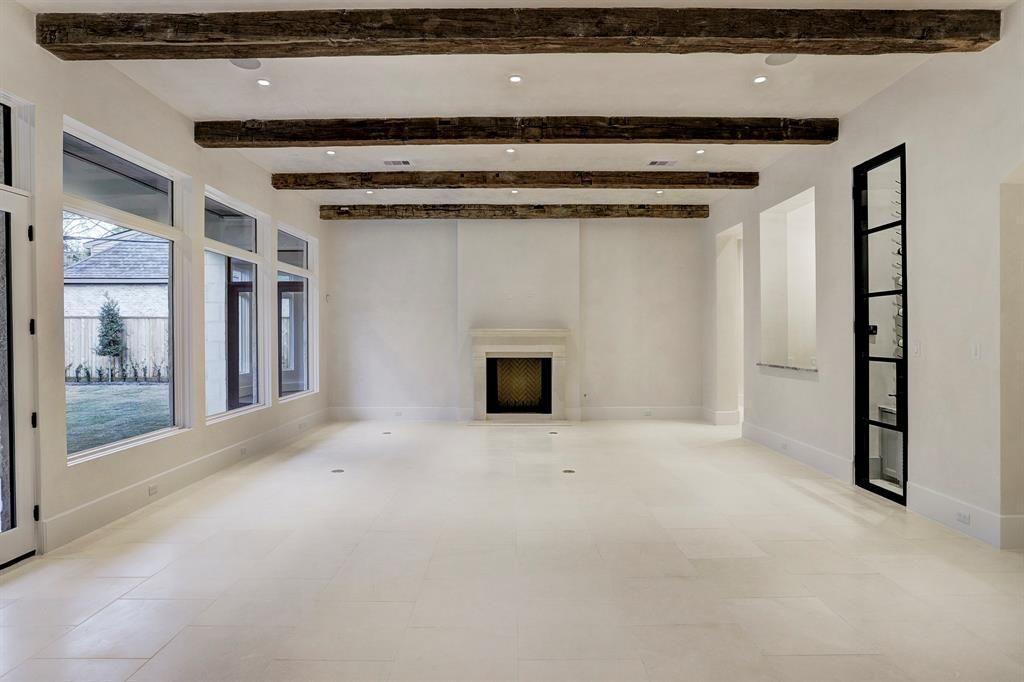 An empty living room with a fireplace and wooden beams.