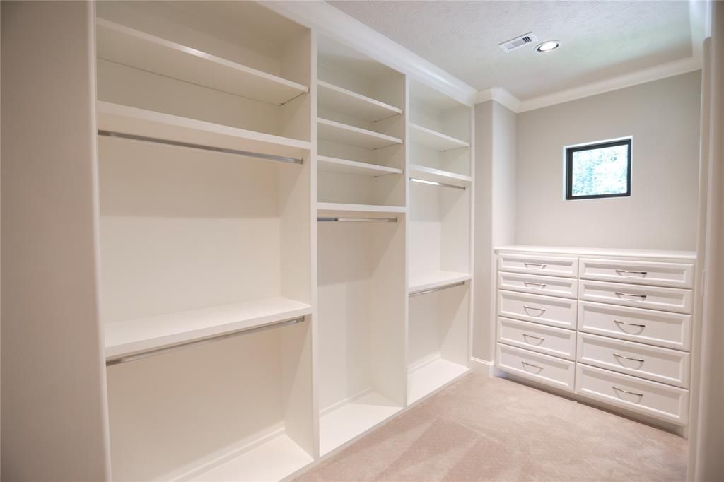 An empty walk in closet with lots of shelves and drawers.