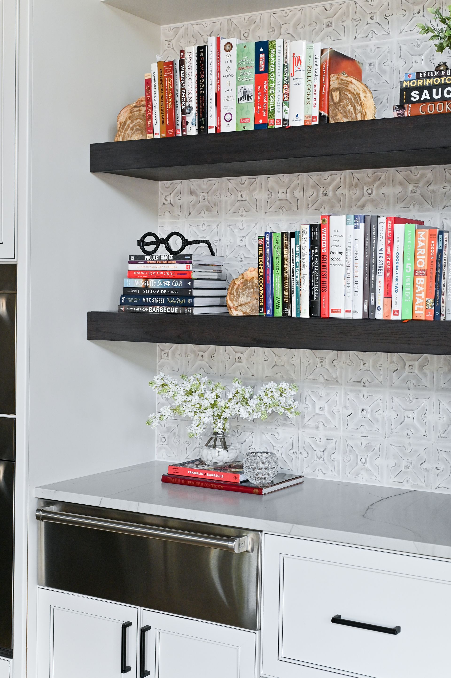 There are many books on the shelves in the kitchen.