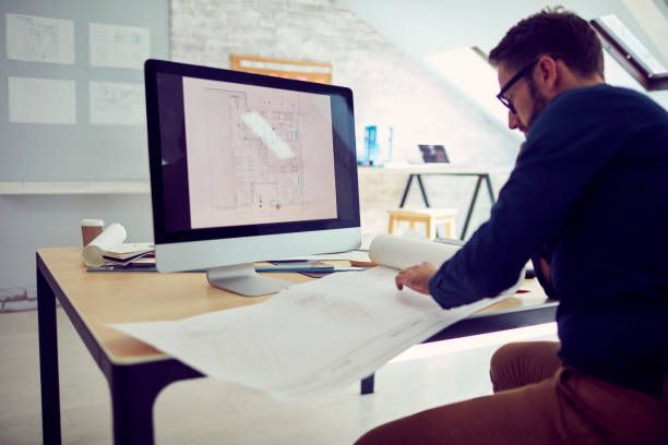 A man is sitting at a desk looking at a computer screen.