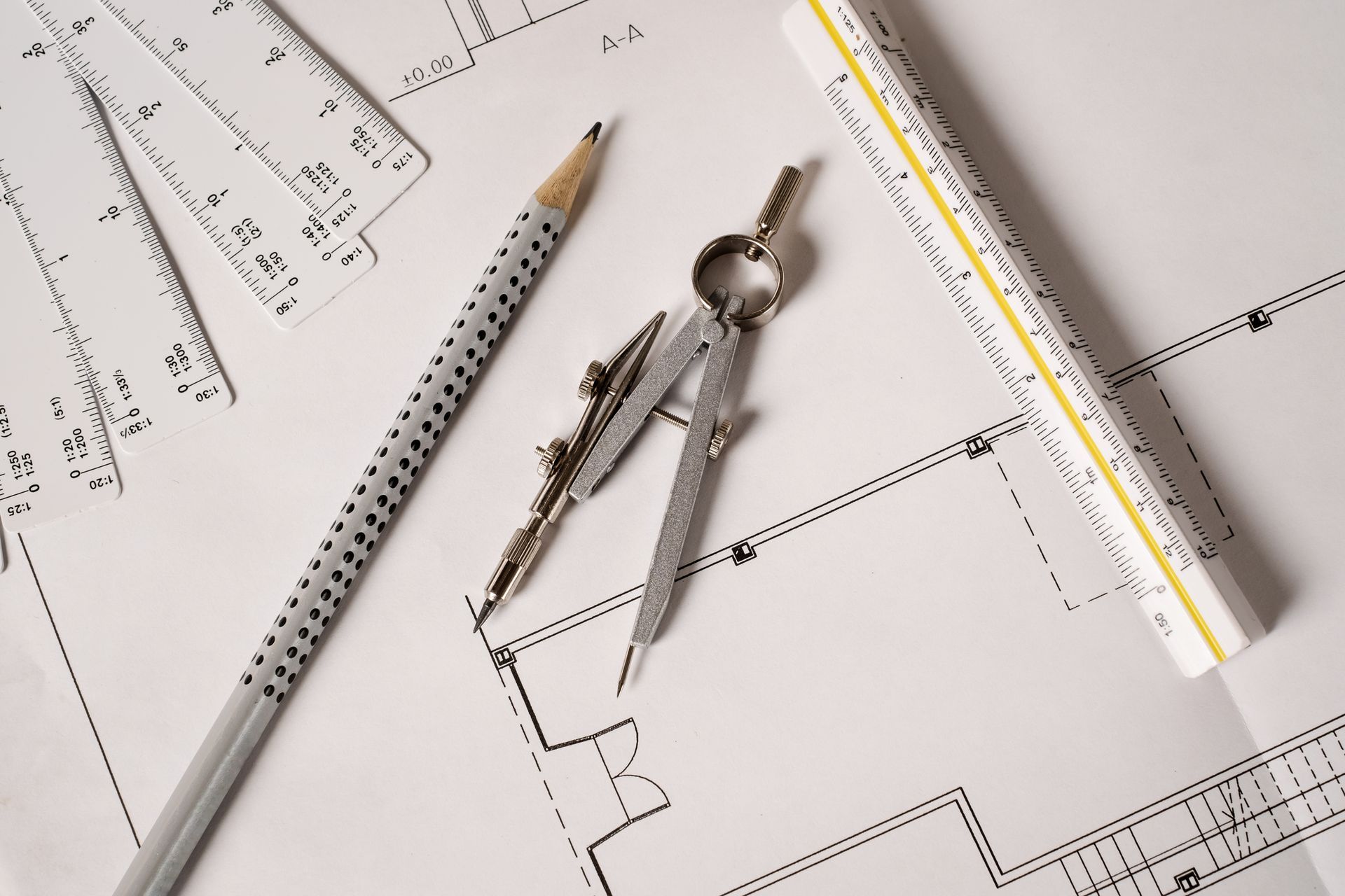 A compass , ruler and pencil are on top of a drawing