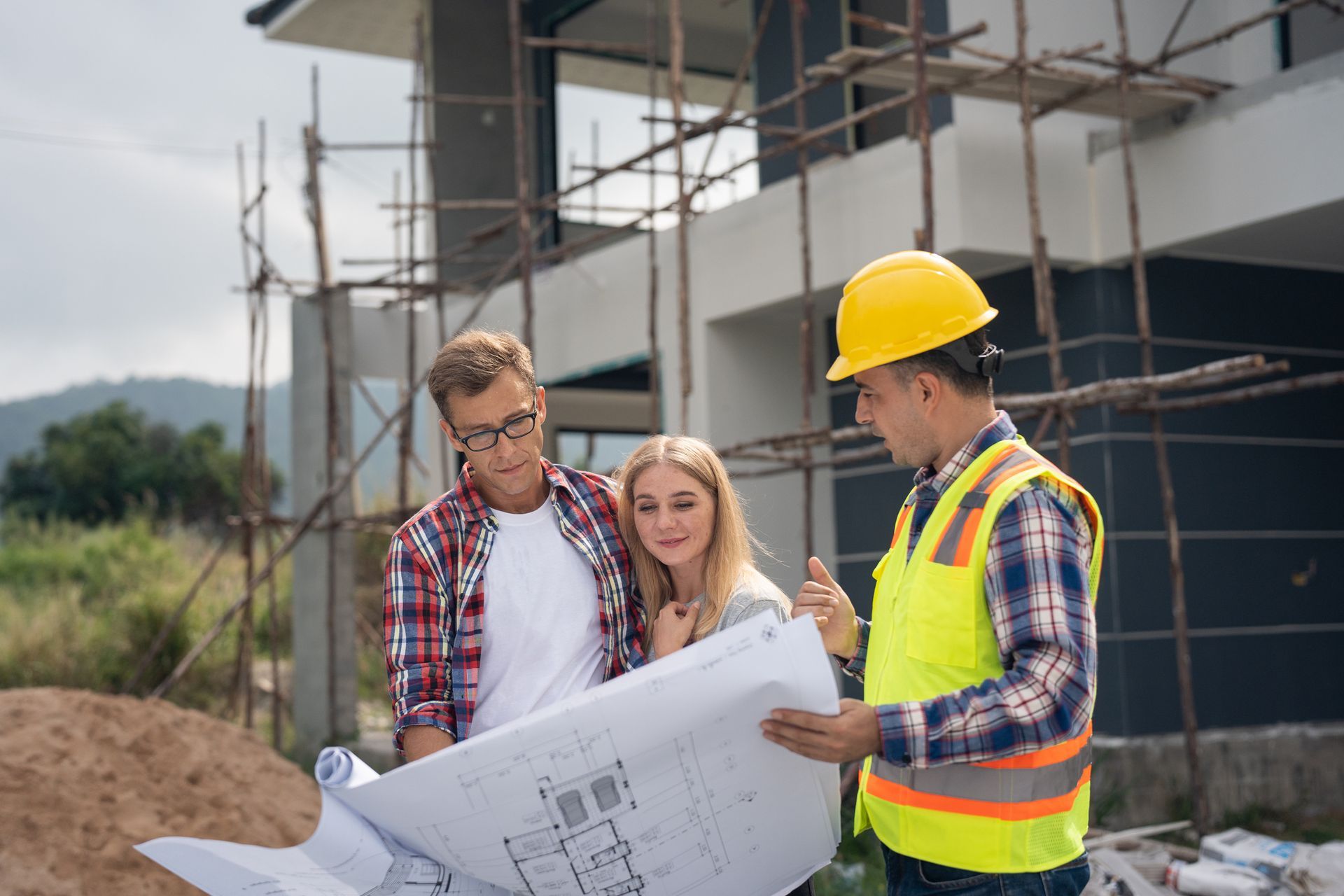 A man and a woman are looking at a blueprint at a construction site.