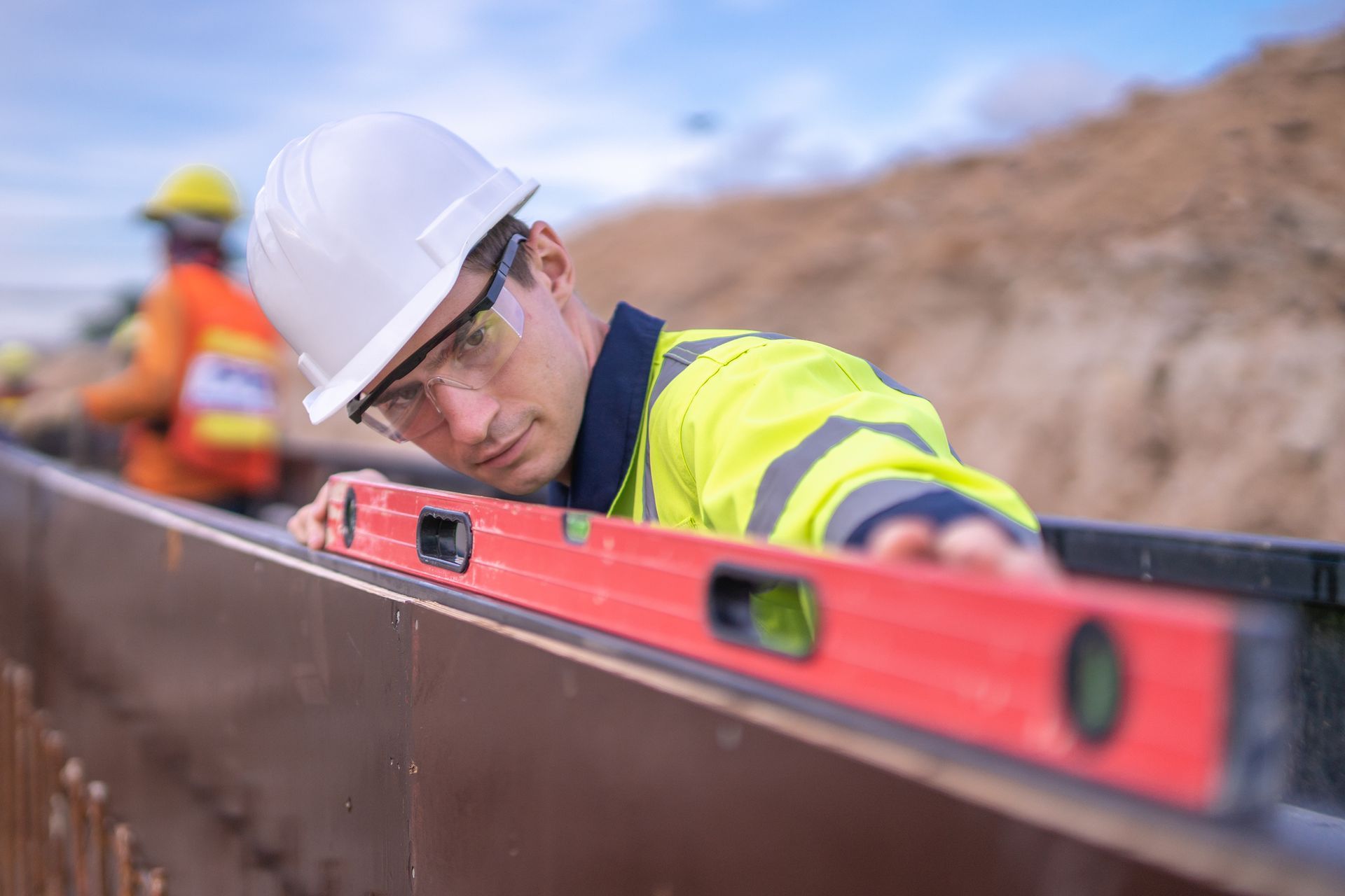 A construction worker is using a red level to check the level of a wall.