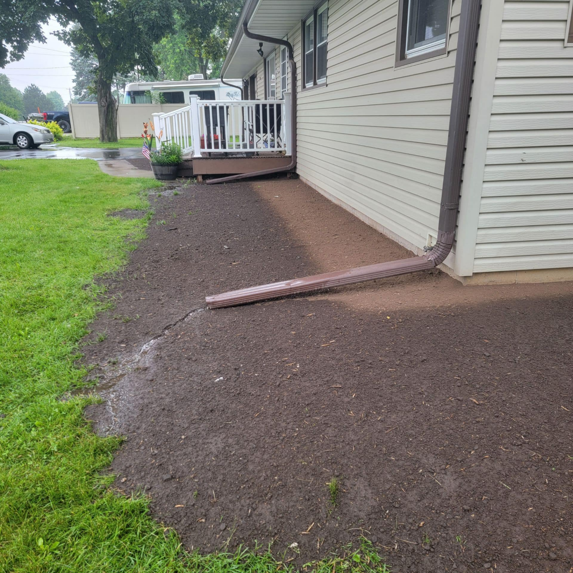 A white house with a long brown gutter on the side of it