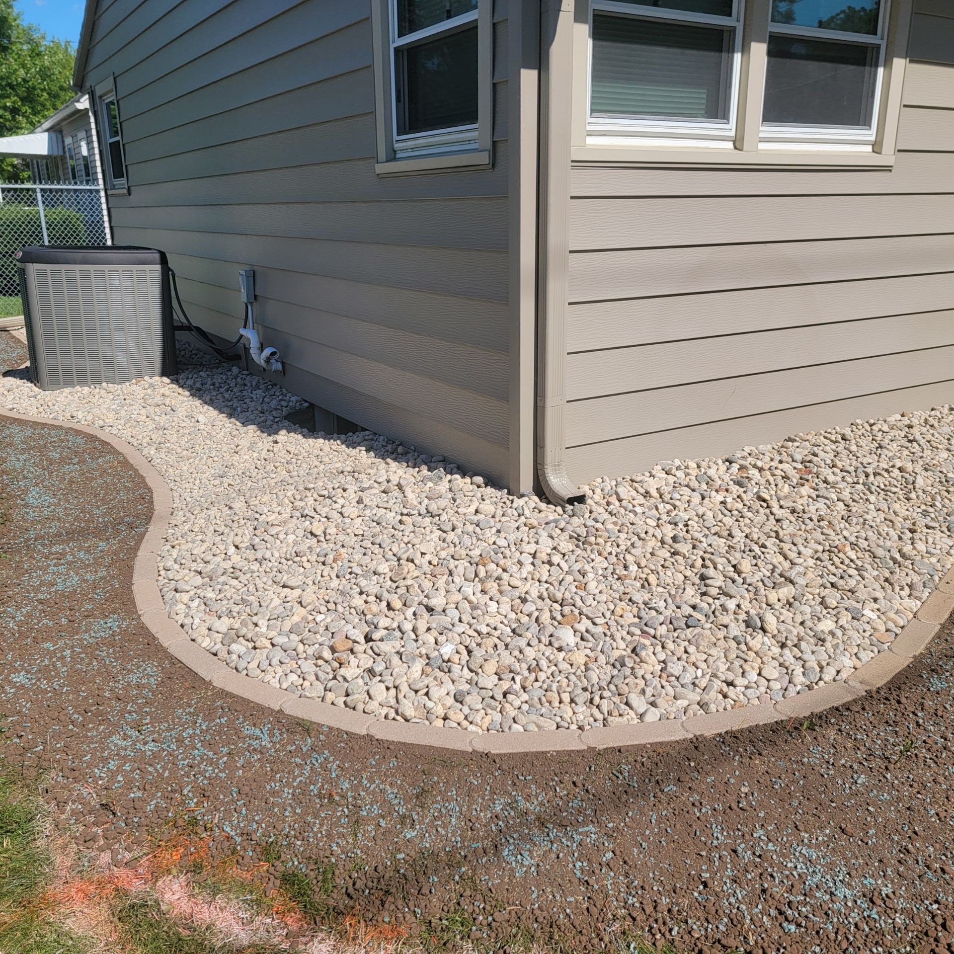 Finished rock bed with landscape edging around a Janesville, WI home to improve drainage and reduce foundation maintenance.