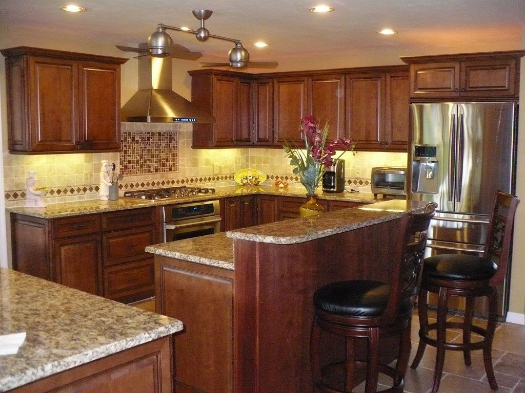 Modern kitchen with dark wood cabinets, granite countertops, stainless steel fridge, and center island with stools