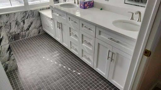 White bathroom vanity with double sinks, large mirror, and gray mosaic tile floor.
