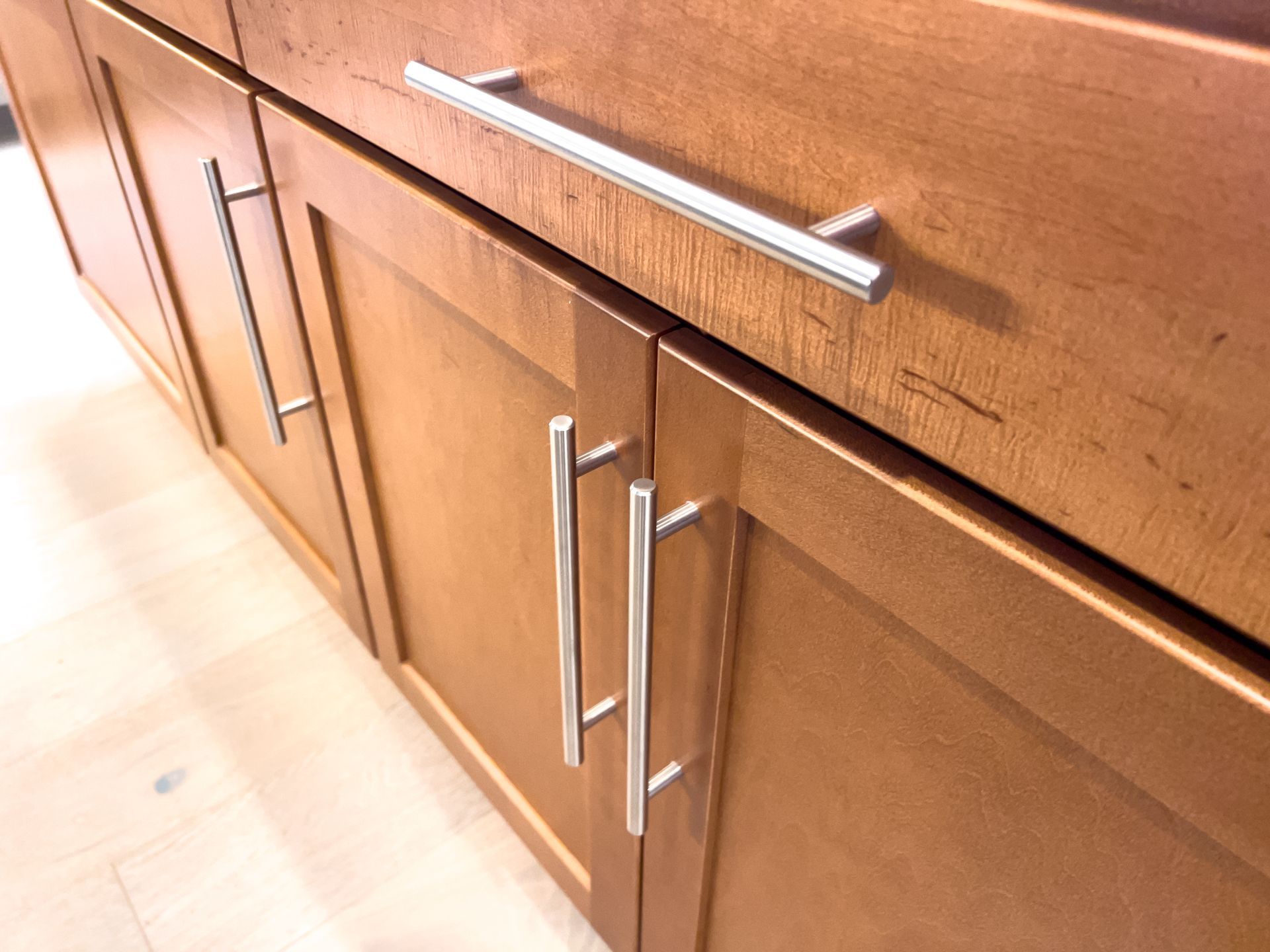 Wooden kitchen cabinets with long silver handles along a countertop.