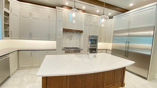 Bright modern kitchen with white cabinets, marble island, and stainless steel appliances