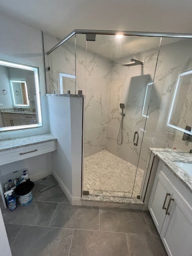 Modern bathroom with tiled walk-in shower, glass door, vanity, and large mirror
