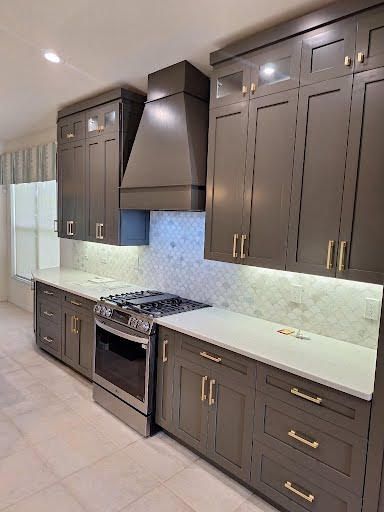 Modern kitchen with dark brown cabinets, white countertops, stainless steel stove, and range hood