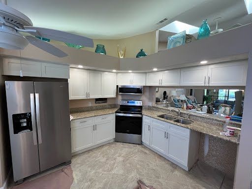 Bright modern kitchen with white cabinets, stainless steel appliances, and granite countertops