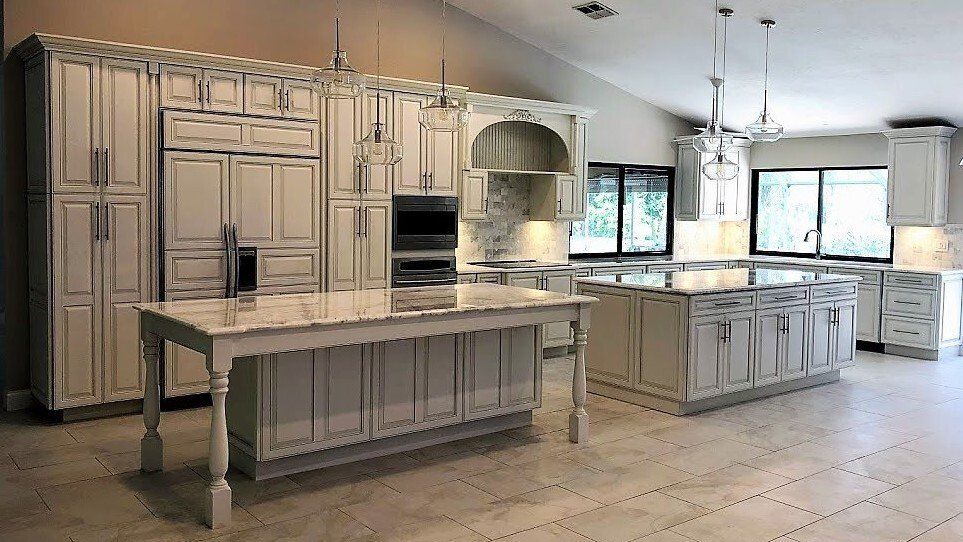 Large bright kitchen with cream cabinets, central island, marble counters, and tiled floor