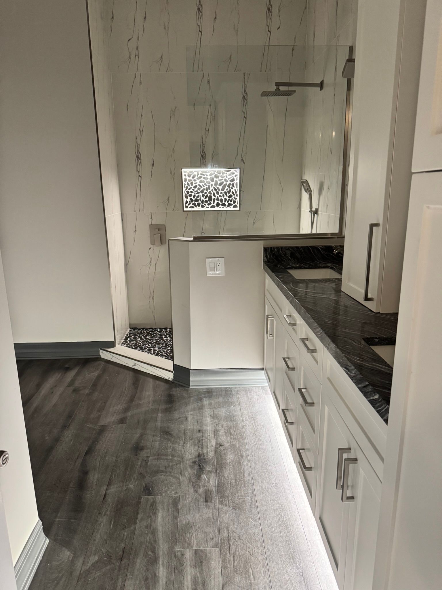 Narrow hallway with wood floor, white cabinets, and a small counter leading to a door with a QR code sign