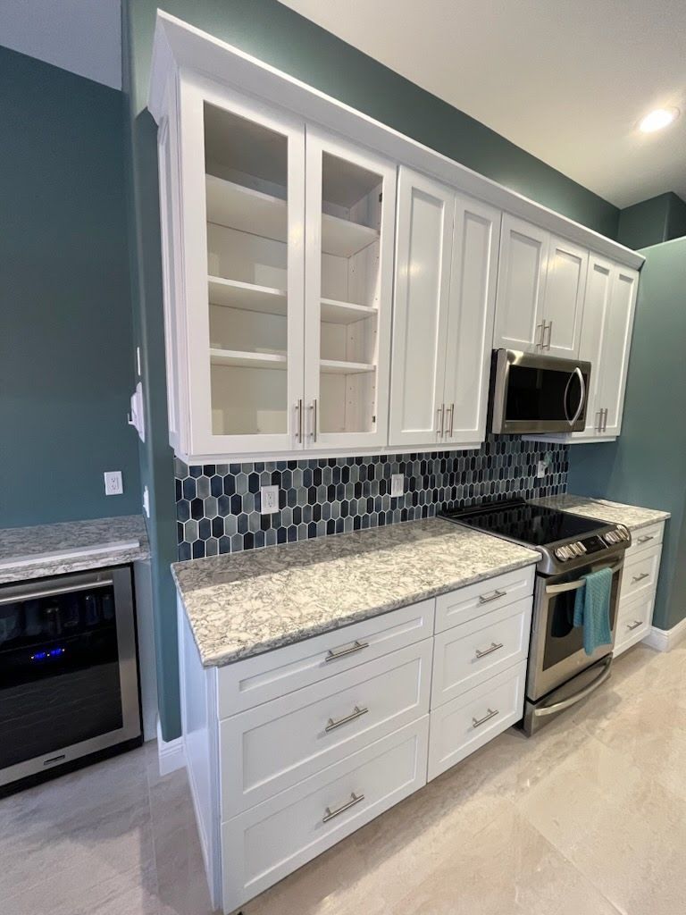 Modern kitchen with white cabinets, granite counters, blue tile backsplash, and stainless steel appliances