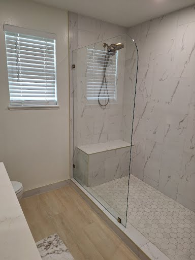 Modern bathroom with walk-in shower, glass door, white tile, and window blinds