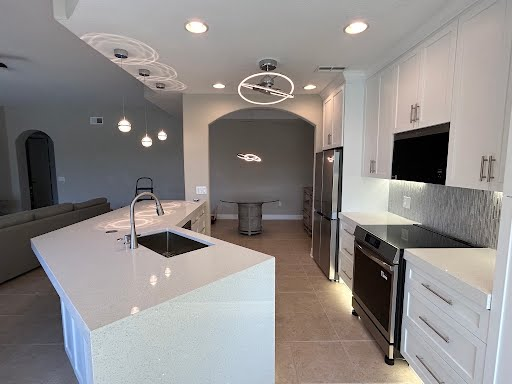 Bright modern kitchen with white island, stainless appliances, and recessed ceiling lights