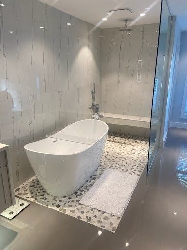 Modern bathroom with a freestanding white tub, mosaic tile floor, and glass shower enclosure