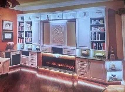 Modern living room with built-in cabinets, fireplace, bookshelves, and warm wood flooring