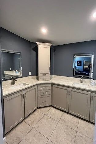 Modern gray kitchen with white countertops, tiled floor, and a central island beneath recessed ceiling lights
