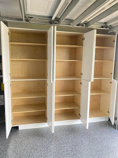 Tall white wooden shelving units in a garage, mostly empty.