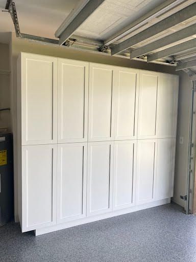 White built-in cabinet wall in a garage with paneled doors and a gray speckled floor