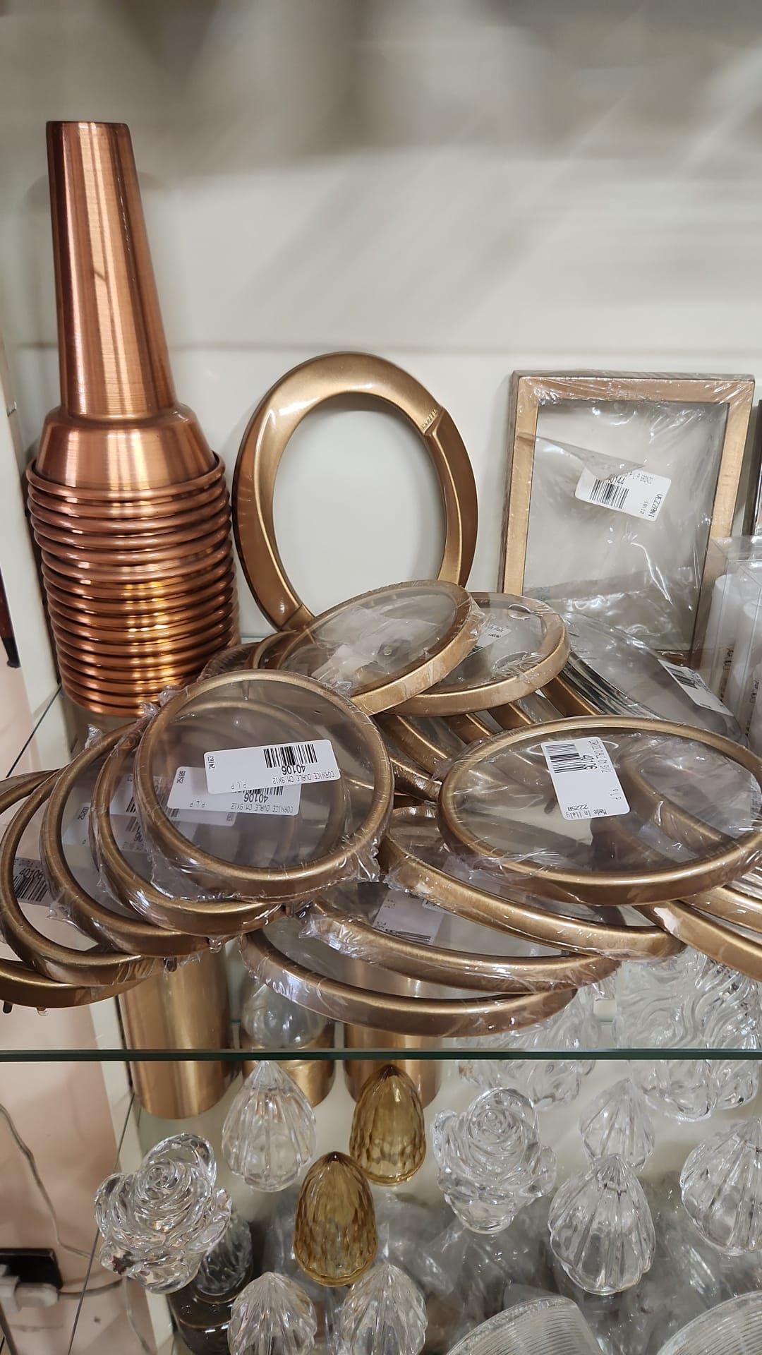 Vasi decorativi in metallo, anelli d'oro e oggetti in vetro esposti sugli scaffali di un negozio.