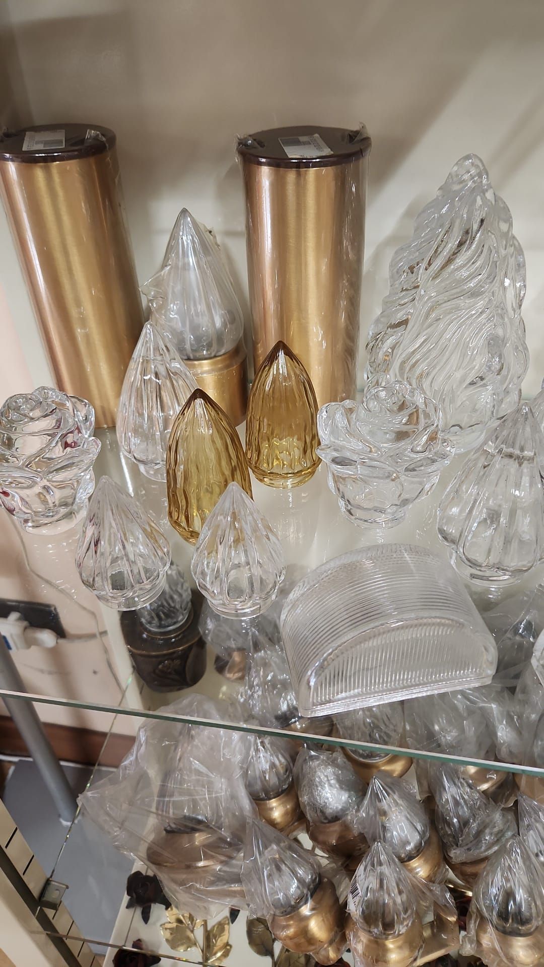 Sculture decorative ad albero in vetro e oro esposte su uno scaffale, con ornamenti d'argento sottostanti.