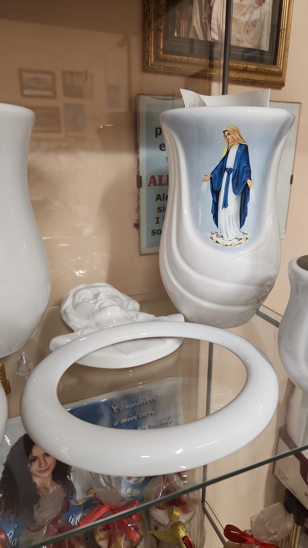 Vaso in ceramica bianca con decorazione a figure blu e oro su una mensola di vetro, accanto a una lampada ad anello rotonda bianca.