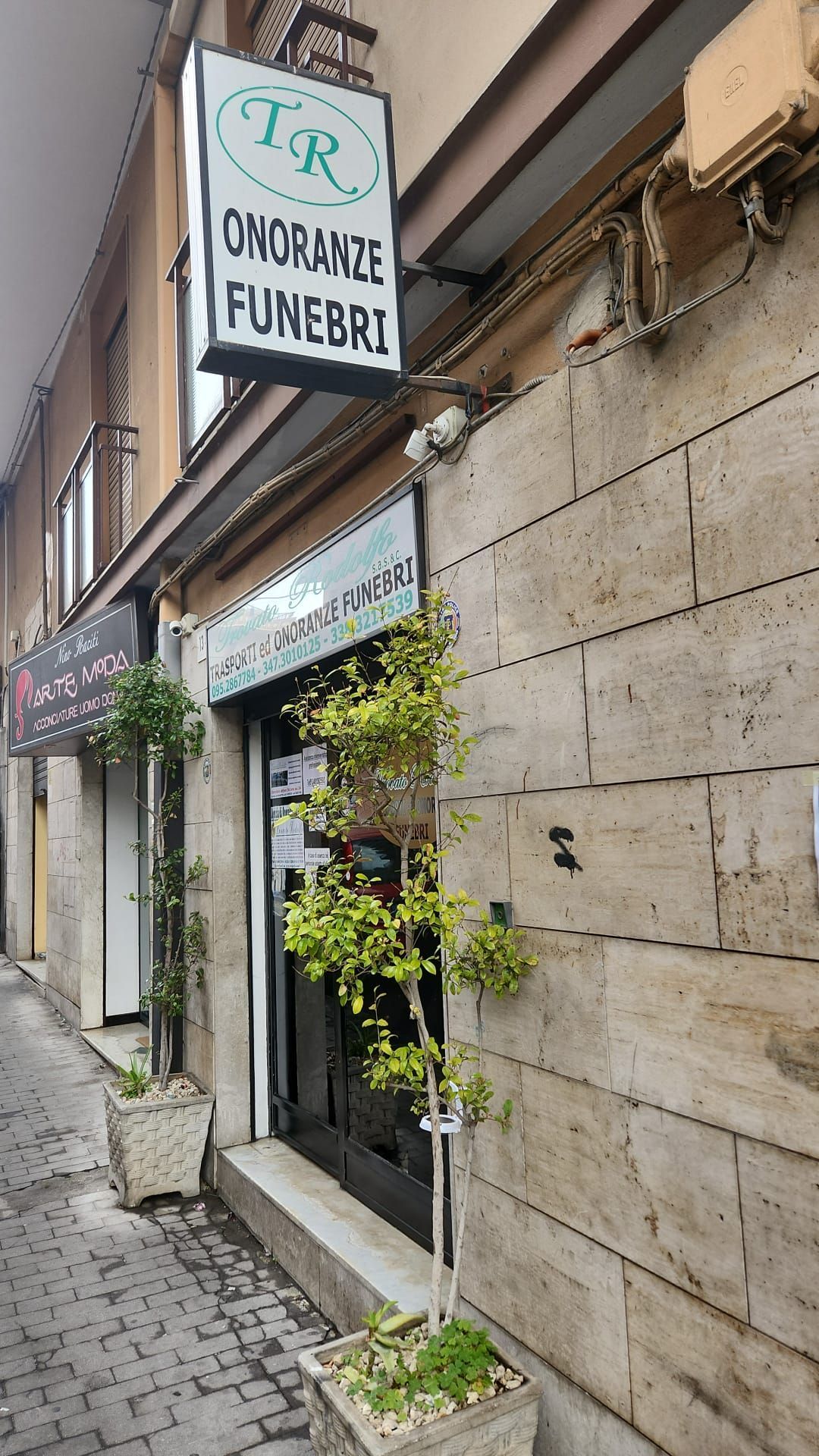 Stretta strada acciottolata accanto a una vetrina con un'insegna appesa con la scritta