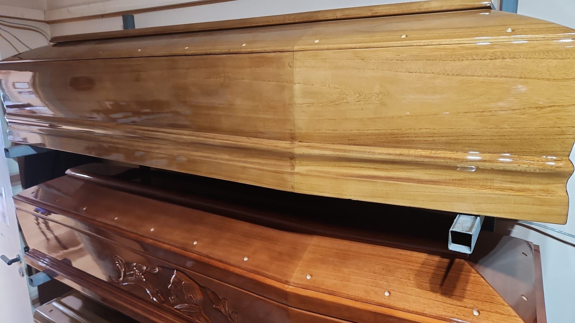 Bare di legno impilate, con finitura lucida, una marrone chiaro e una marrone più scura, in un magazzino.