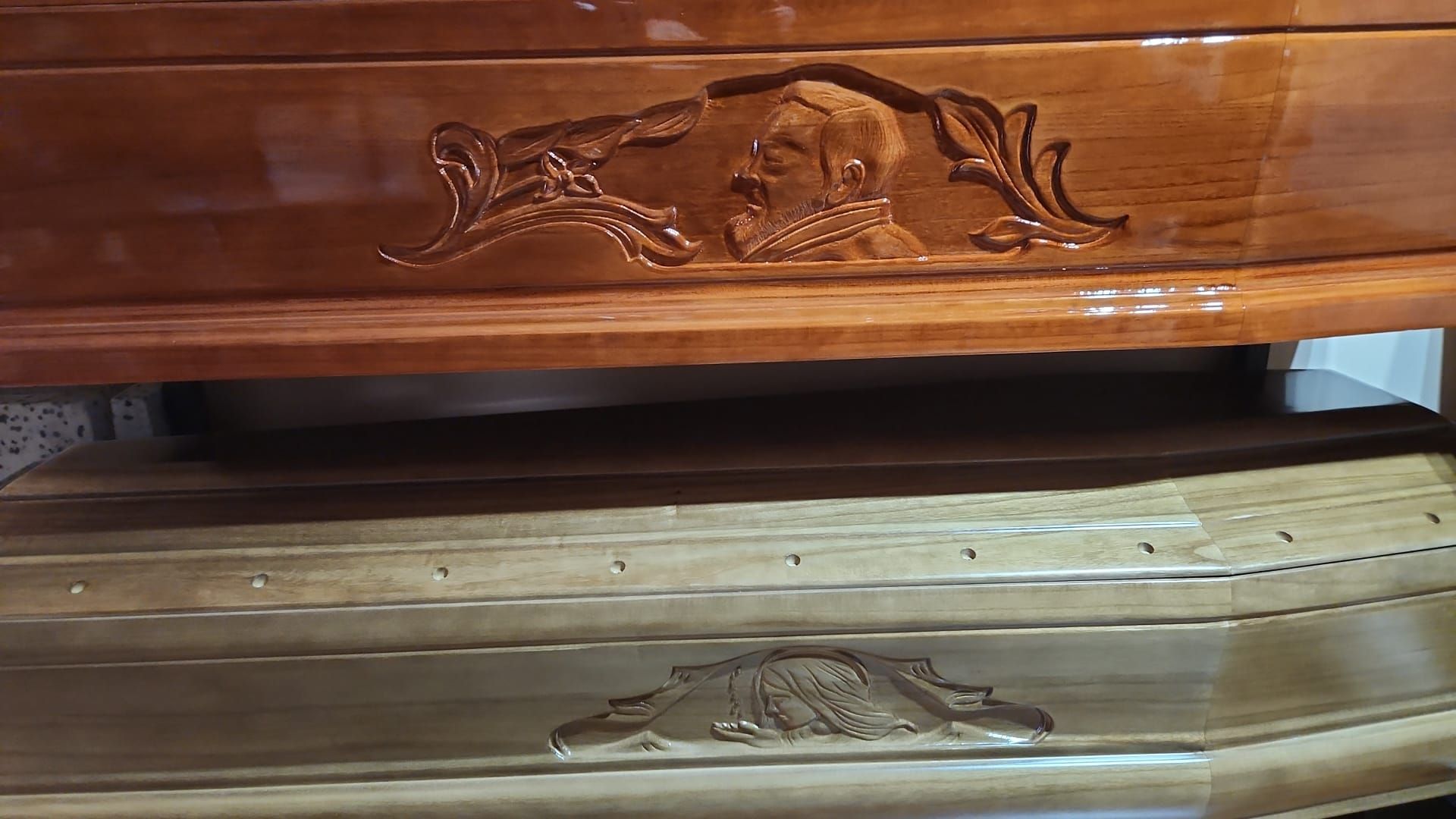Primo piano del frontale di un cassetto di una cassettiera in legno con intagli floreali e spazi aperti tra i cassetti.